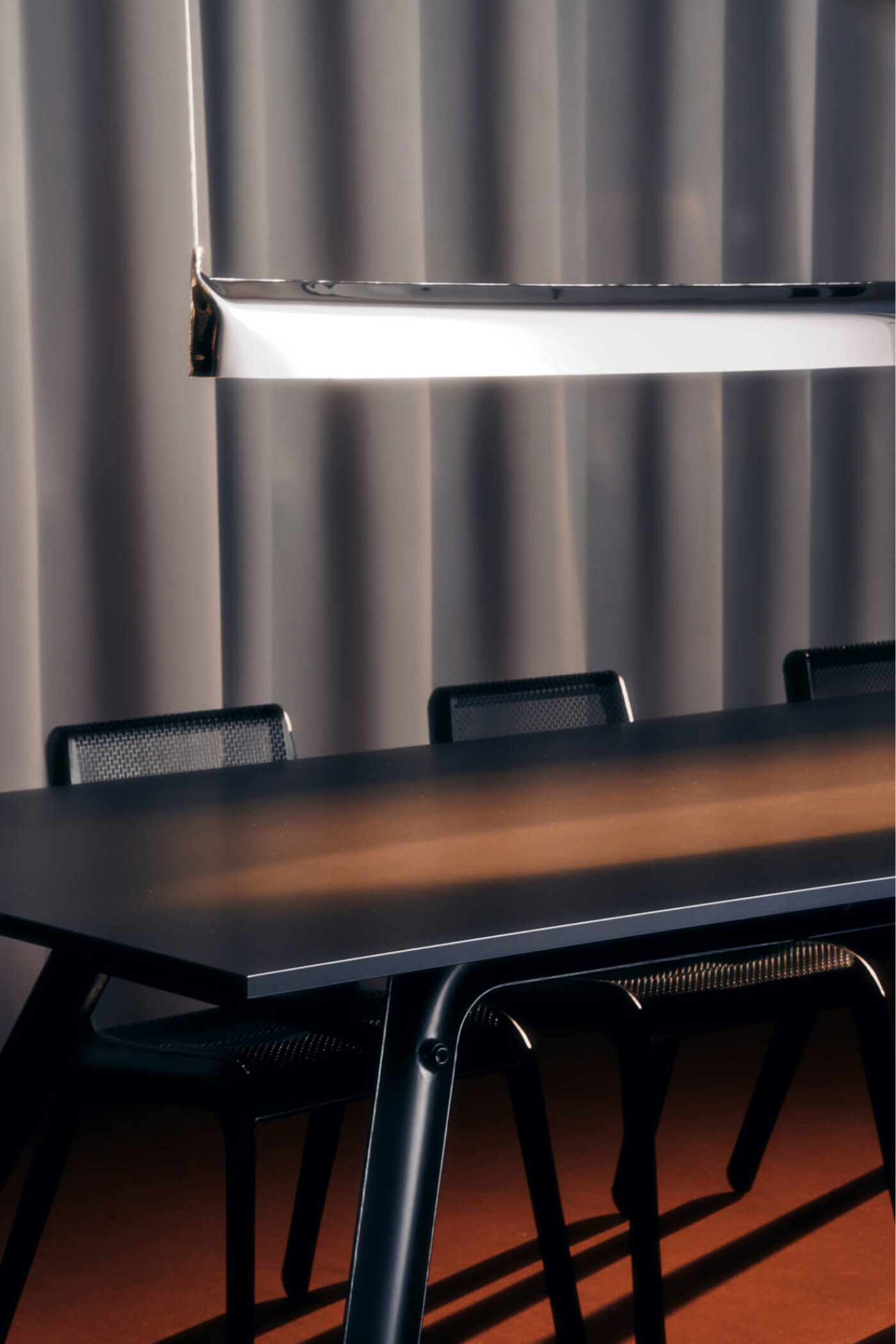 Zieta Studio, Blade lamp in inox finish paired with Ultraleggera chairs in black – minimalist meeting room setup. Polished stainless steel pendant, ultra-lightweight seating, FiDU technology, functional design, modern interior, architectural lighting, industrial style, sculptural furniture, contemporary workspace aesthetics