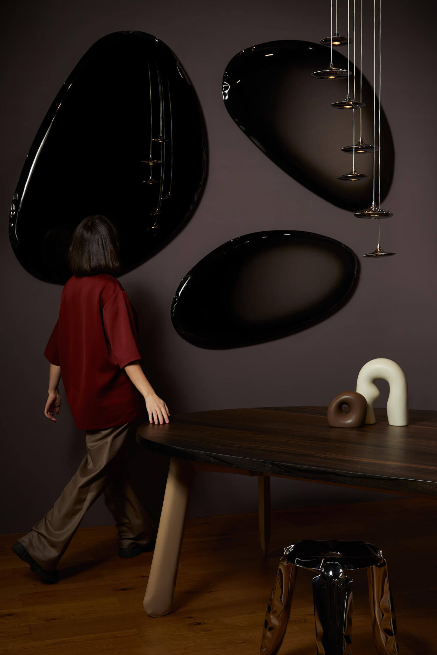 Zieta Studio interior with Tafla mirrors in Deep Space Blue, FiDU technology stainless steel reflections, Plopp stool in polished inox, dark wood table with beige legs, pendant Lampin lights, sculptural accessories on tabletop, modern collectible design