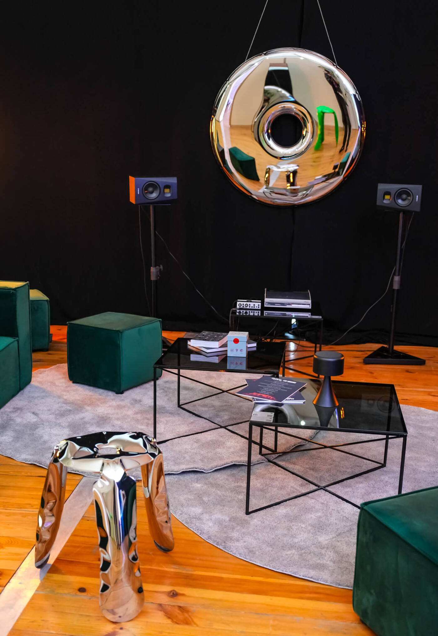 Polished stainless steel Plopp stool and Rondo mirror by Zieta Studio, created using FiDU technology, displayed in a contemporary lounge with wooden flooring and designer furniture.