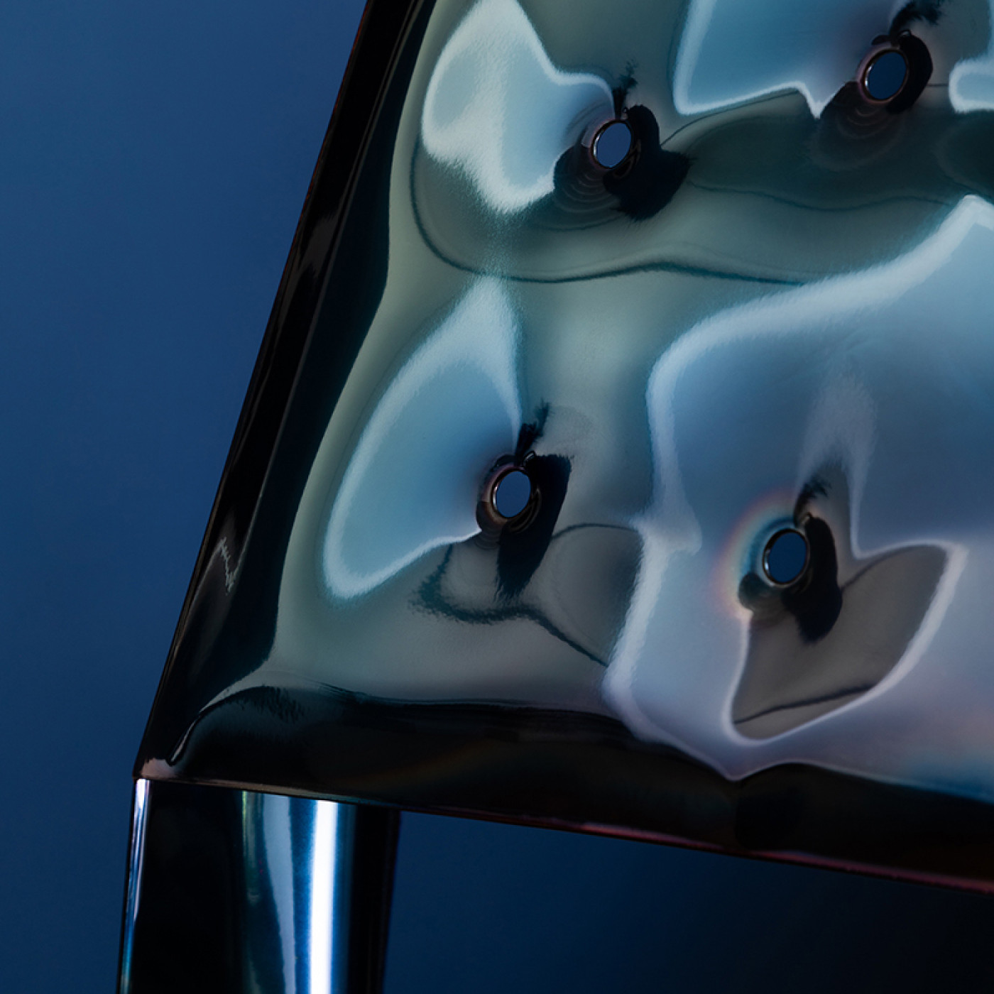 Zieta Studio: detal oparcia, close-up of Chippensteel chair color deep space blue; futuristic form, polished steel, light reflections, modern elegance, metallic depth, unique design, artistic craftsmanship