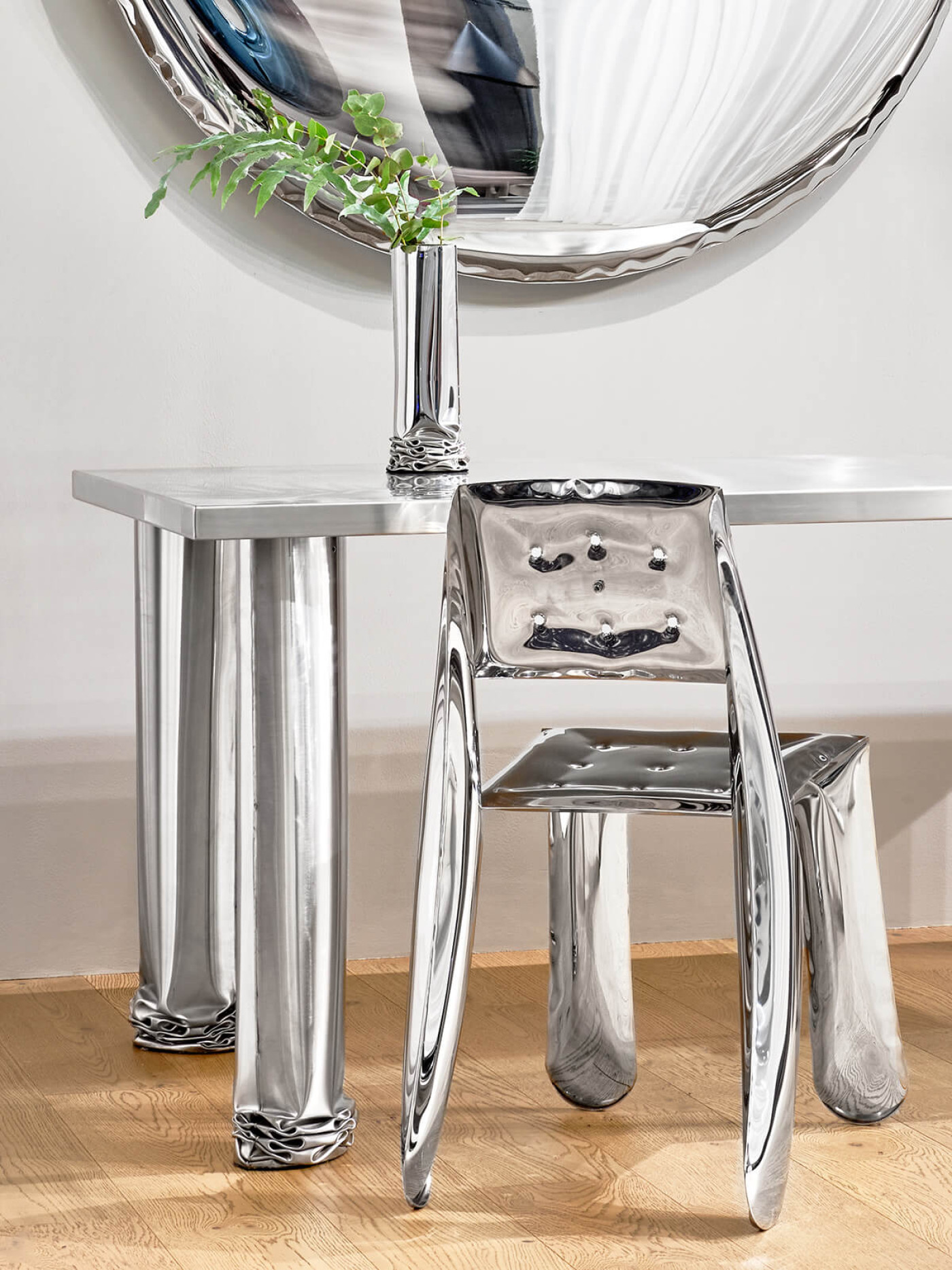 a steel objects as a chair, mirror, table and a vase in interior setting 